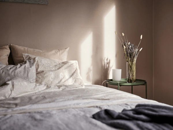 Un protector de colchón limpio colocado sobre una cama moderna con sábanas blancas.