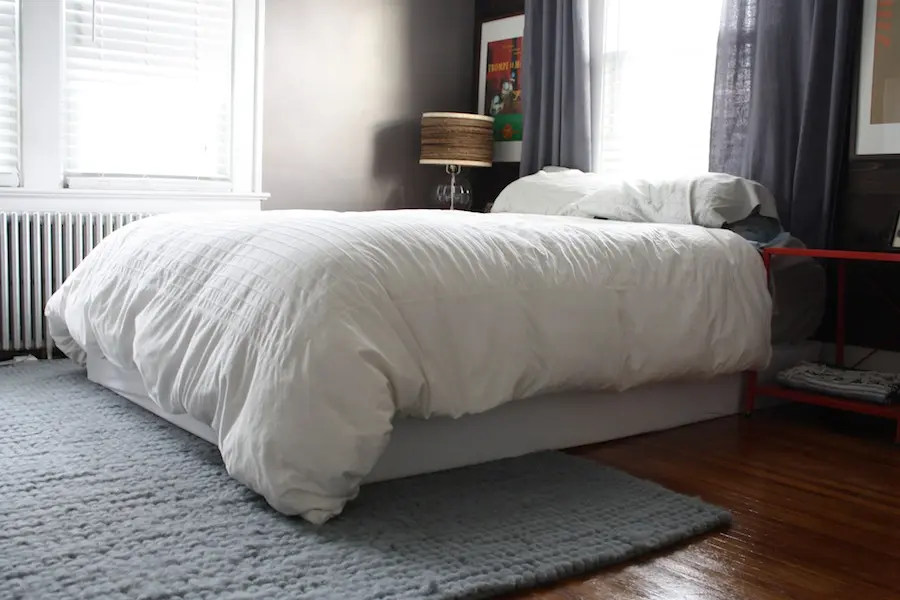 Modern bedroom bed with a box spring cover installed, showing a tidy under-bed area and replacing a traditional bed skirt