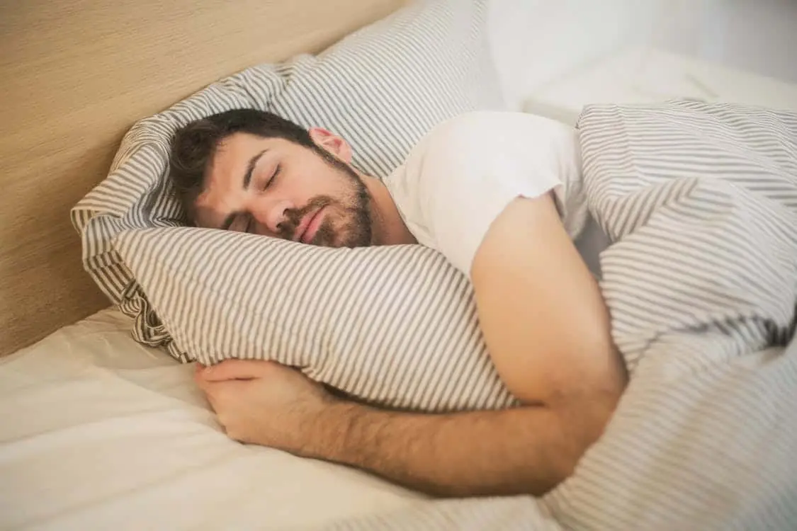 Personne dormant paisiblement sur une literie claire et respirante conçue pour les peaux sensibles, garantissant une nuit de repos confortable