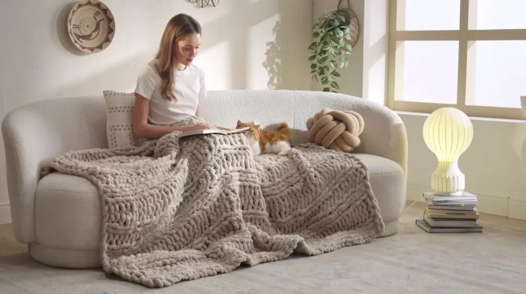 Stylish grey chunky knit blanket with large, distinct stitches, adding a cozy texture to home decor