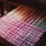 Close-up of a loom weaving warp and weft yarns to create woven fabric