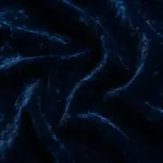 Primer plano de una tela de terciopelo azul profundo arrugado que resalta su pelo de textura irregular y su brillo variable que refleja la luz.