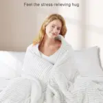 Une femme se détend sous une couverture polaire Sherpa tout en lisant sur le canapé