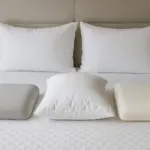 Différents types d'oreillers, notamment en mousse à mémoire de forme, en latex et en duvet, sont présentés sur un lit pour les personnes dormant sur le côté et sur le dos.